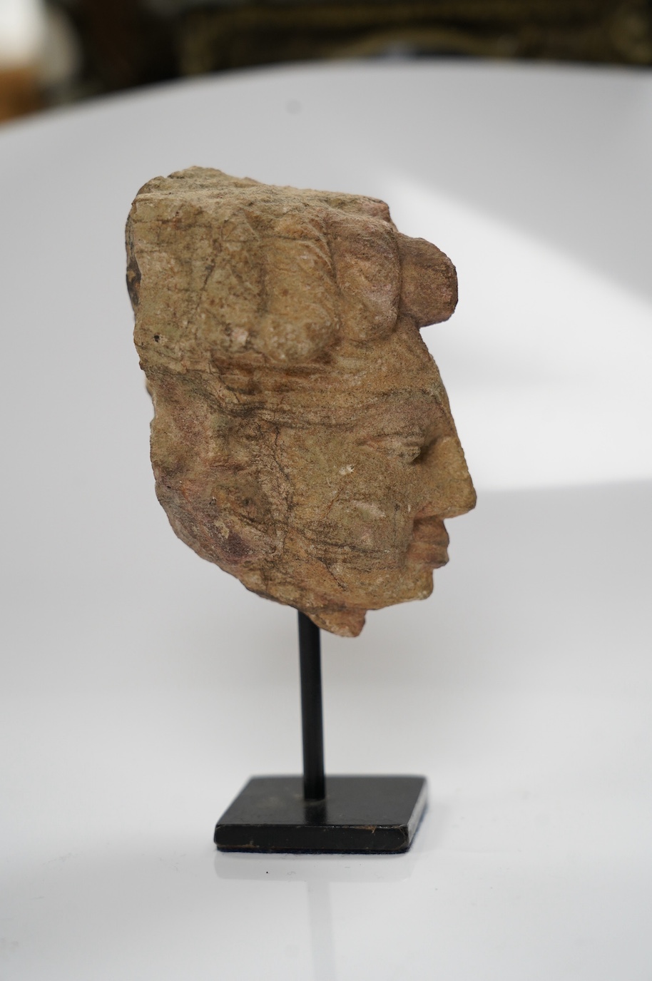 An Indian sandstone head of Shiva, 16th century, 8cm not including stand. Condition - good considering age